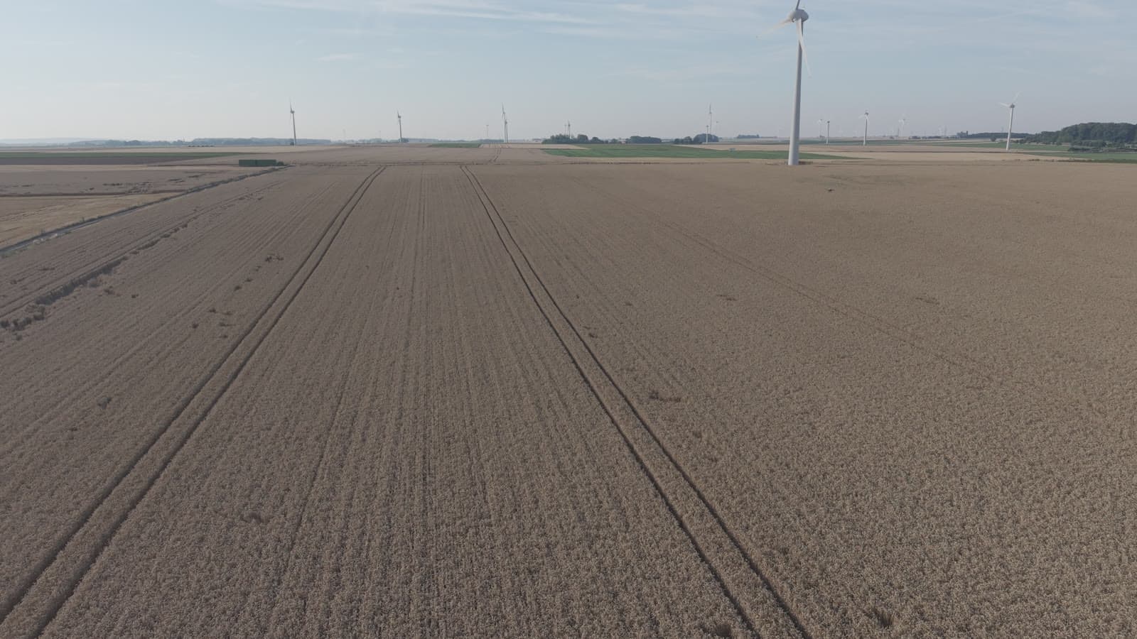 Parcelle agricole vue du ciel, éoliennes à l’horizon